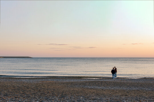Coppia in lontananza controluce al tramonto sulla spiaggia di fronte al mare