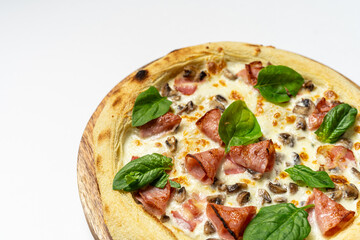 Tasty whole Italian pizza topped with thinly sliced prosciutto ham on the served restaurant table. Selective focus