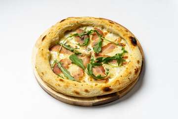 Tasty whole Italian pizza topped with thinly sliced prosciutto ham on the served restaurant table. Selective focus