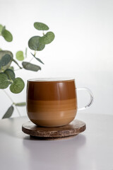 Cafe latte macchiato layered coffee in a see through glass coffee cup. The cup is on a white background .