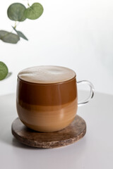 Cafe latte macchiato layered coffee in a see through glass coffee cup. The cup is on a white background .