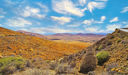 Beautiful wild arid valley landscape, serpentine road, blue sky fluffy clouds - Betancuria (montana atalaya), Lanzarote