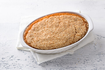 Delicious healthy gluten free lentil bread without flour with sesame seeds in a white baking dish on a light gray background. homemade vegetarian food