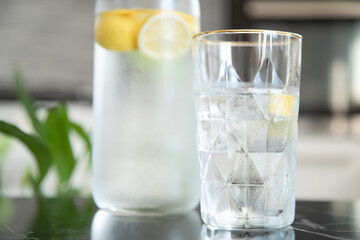 Glass with lemonade with lemon in the kitchen. Summer refreshing drink. Fresh homemade lemonade with lemon slices