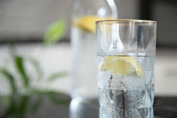 Glass with lemonade with lemon. Fresh healthy cold lemon beverage. Water with lemon. Homemade lemonade.