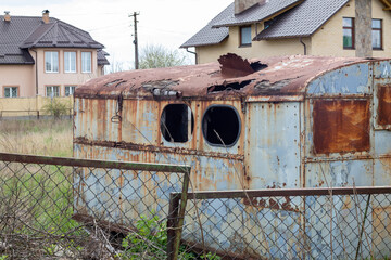 A dilapidated rotten and rusty metal hut on a work site. An old tin construction trailer with a...