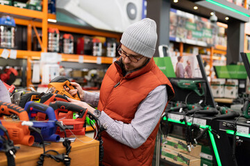 Obraz premium a man in a hardware store chooses a jigsaw