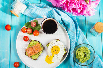 sandwich with fried egg, avocado and salted salmon with a cup of aromatic coffee for breakfast