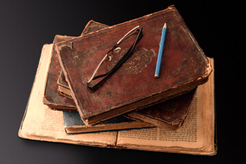Stack of old worn jewish books in leather binding on open Torah pages on dark background. Closeup....