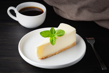 Cheesecake and cup of black coffee on a wooden table