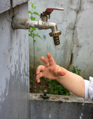 Close up of a child's hand playing with water from a garden faucet