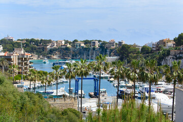 Porto Cristo, Mallorca, Spain - 05.02.2022: Yachts and boats in port of Porto Cristo. Houses on cliffs in background