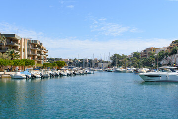 Fototapeta na wymiar Porto Cristo, Mallorca, Spain - 05.02.2022: Yachts and boats in port of Porto Cristo. Houses on cliffs in background