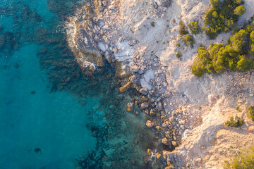 Fototapeta na wymiar Aerial top down view of waves crashing against rocks in turquoise sea water