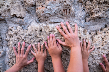 Hands of a woman and children on the background of an old wall