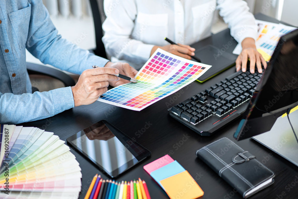 Poster Team graphic designer working on document of color chart to brainstorming about new project and using laptop