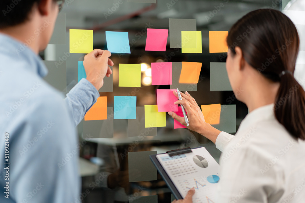 Poster two business executive team holding and taking notes keyword on board wall to brainstorm about a new
