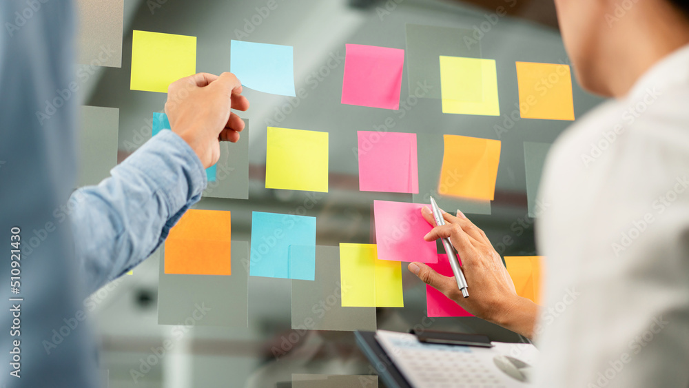 Poster two business executive team holding and taking notes keyword on board wall to brainstorm about a new