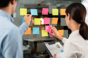 Two business executive team holding and taking notes keyword on board wall to brainstorm about a...