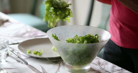 Serving salad into plate close-up lunch