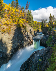 Portrait, long exposure shot of waterfall in Yukon Territory during fall, autumn season. 