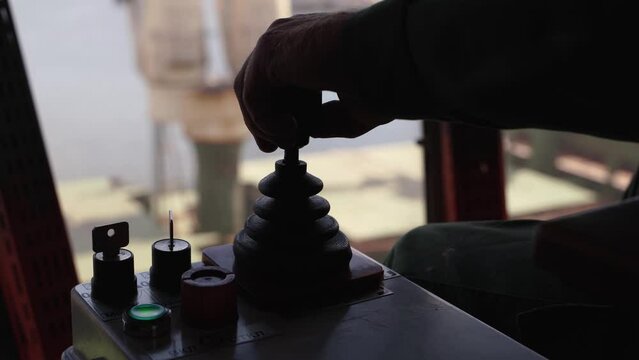 Man hands control joysticks at grain terminal operator cabin workplace. Worker controlling loading grain with arm lever handle from silo to bulker ship via moving trunk machine in dock.