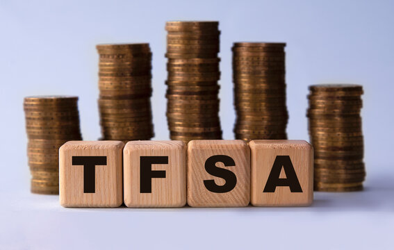 TFSA - acronym on wooden cubes on the background of stacks of coins