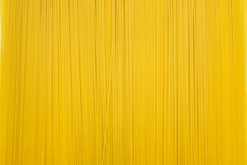 Background of long dry spaghetti arranged vertically. Italian traditional wheat dish. Free space for text and advertising. Long narrow spaghetti ready to cook