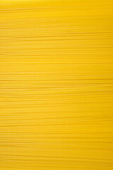 Background of long dry spaghetti arranged horizontally on a vertical photo. Traditional Italian wheat dish. Free space for text and advertising. Long narrow spaghetti ready to cook