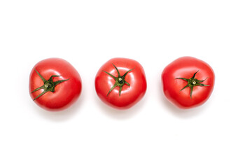 Three fresh tomatoes on a white isolated background. Fresh juicy tomatoes with green stems ready to eat or ingredient for cooking. Three tomatoes in a row top view