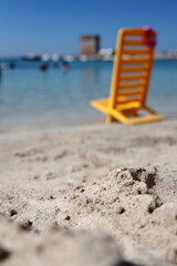 Fototapeta na wymiar Sand on the beach with a blurred chair, and blue sky