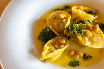 Artistic gourmet food background, Italian ravioli with peanuts and creamy spinach decoration. White plate and fresh paste. Restaurant table top view, traditional close fresh delicious tasty stuffed