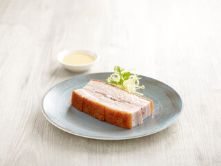 Crackling Pork Belly Served in a dish isolated on wooden board side view on grey background