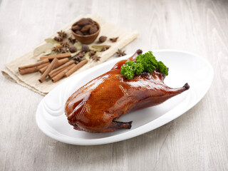 Crispy Roasted Irish Duck (Whole) Served in a dish isolated on wooden board side view on grey background