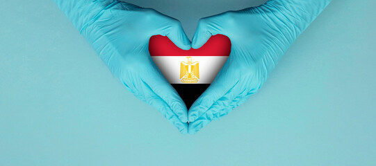 Doctors hands wearing blue surgical gloves making hear shape symbol with egypt flag