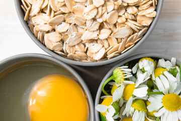 Close-up of natural ingredients for making homemade cosmetics. Chamomile flowers, oatmeal and egg...