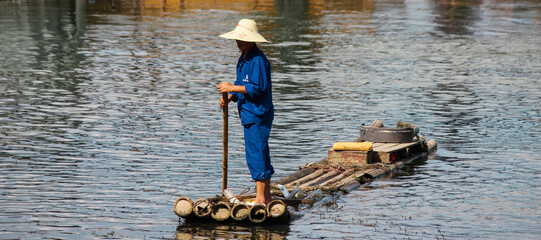 photograph of an unrecognizable blue dressed chinese fisherman on the li river in china