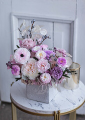 Light gray concrete planter with flowers. Gently pink anemones, pink roses and cream peonies with eucalyptus. Composition on a marble table. Floristics preserved flowers.