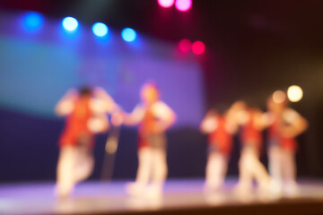A colored blurry background of a dance festival from a group of little girls. Bright stage lighting. Silhouettes of little dancers. High quality photo