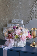 Beautiful bouquet of flowers in basket on blue table. Wicker basket whit preserved flowers. Floristry concept.
