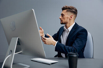 handsome businessman tired glass of coffee works in front of a computer Gray background