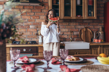 Woman at home eating watermelon in the kitchen