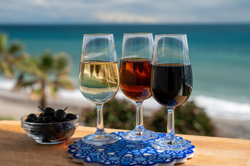 Tasting of Spanish sweet and dry fortified Vino de Jerez sherry wine and green olives with view on blue sea near El Puerto de Santa Maria, Andalusia, Spain
