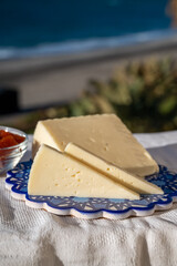 Spanish hard goat cheese served outdoor with membrillo jam with blue sea on background