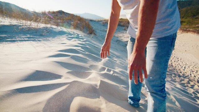 Man plays with sand on the sandy dune