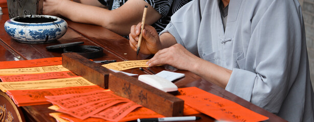 Chinese craftsman making calligraphy with some red and white papers