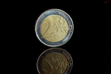 Close up of a 2 Euro coin against a black background with a reflection