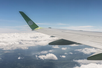 Wing aircraft in altitude during flight. Flight and travel, the view from the window of the plane to the wing of the plane above the ground and clouds. Flying in the sky.