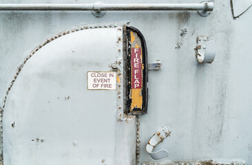Fire flap emergency door on an old rusting boating vessel 