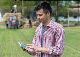 Fototapeta premium Farmer standing on ranch and working on tablet